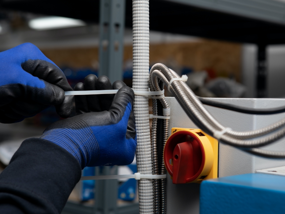 Instalador fijando cableado con bridas blancas en instalación eléctrica