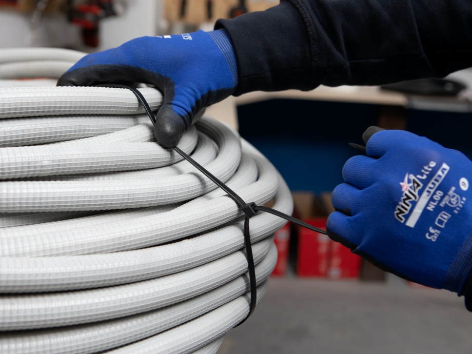 Installer fastening flexible pipe using black cable ties